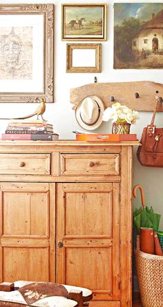 a wooden dresser sitting next to a wall filled with pictures and other things on top of it