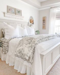 a large white bed sitting in a bedroom next to a window