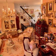 a living room filled with furniture and lots of pictures on the wall next to stairs