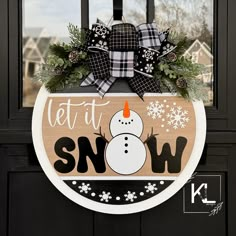 a wooden sign with a snowman on it that says let it snow and is hanging from the front door