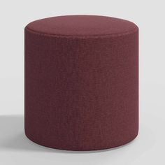 a small round ottoman in maroon fabric