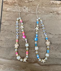 two bracelets with beads and seashells hanging from them on a stone wall