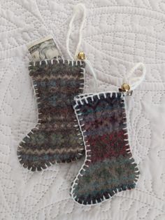 two knitted mittens hanging from strings on a quilted tablecloth with money in the background