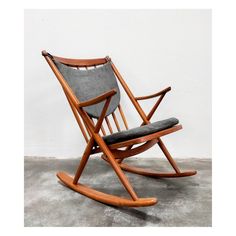 a wooden rocking chair sitting on top of a cement floor next to a white wall