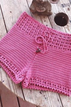 a pink crocheted skirt sitting on top of a wooden table