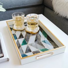 two glasses are sitting on a tray that is decorated with marble and gold trimmings