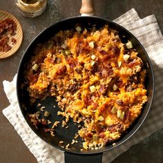 a skillet filled with food sitting on top of a table next to a wooden spatula