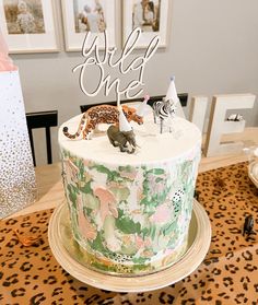 a birthday cake with animals on top and the word wild one written in white frosting