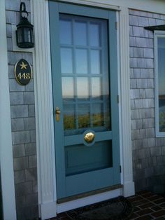 a blue front door with two windows and a light on the side walk next to it