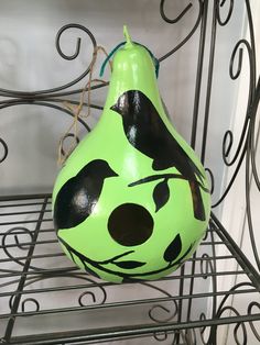 a green and black vase sitting on top of a metal rack next to a wall