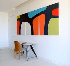 two paintings are hanging on the wall next to a table with chairs in front of it