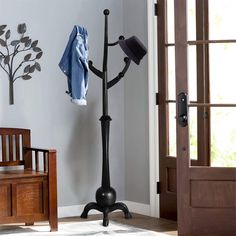 a coat rack with hat and jacket on it in the corner of a living room