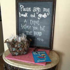 a table with a chalkboard and some candy on it next to a sign that says please sign my book and grub