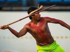 a man with tattoos holding a stick in his right hand and painted on his left arm