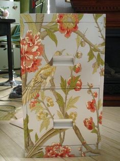 a bird painted on the side of a white box with flowers and branches around it