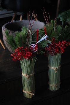 two green vases with red berries and greenery in them sitting on a table