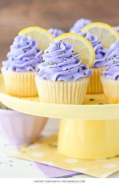 cupcakes with purple frosting and lemon slices on a yellow cake platter