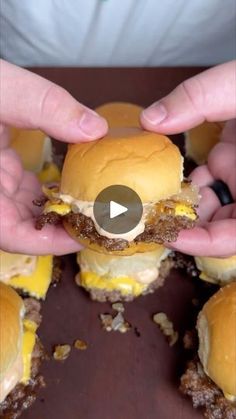 two hands holding hamburgers with cheese on them