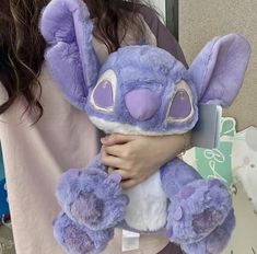 a woman holding a purple stuffed animal in her hands