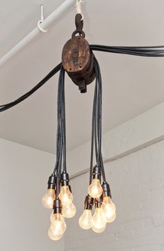 a chandelier with five lights hanging from it's sides and cords attached to the ceiling