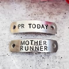 two metal tags that say pr today and mother runner