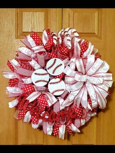 a red and white wreath with baseballs on the front door, decorated with ribbon