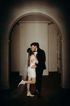 a bride and groom kissing in an archway