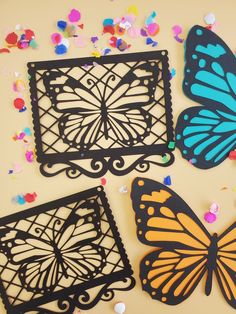 three butterfly cut outs sitting on top of a table next to confetti sprinkles