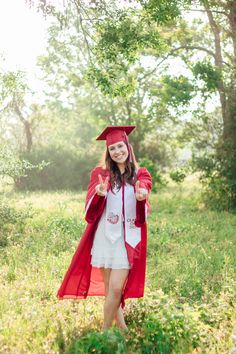 a woman in a graduation gown and cap is giving the peace sign with her hand