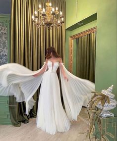 a woman in a white wedding dress is holding her long flowing veil over her shoulders