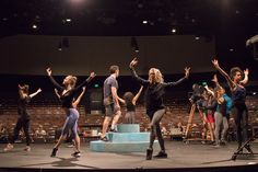 a group of people standing on top of a stage with their hands in the air