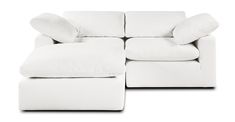 a white couch with pillows on it and a footstool in front of it