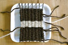 a weaving project on a plate with twine and yarn in the shape of a rectangle