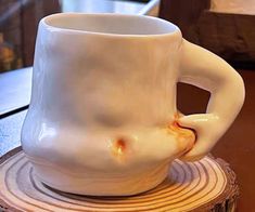 a white coffee cup sitting on top of a wooden table next to a tree stump