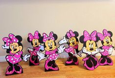 a group of minnie mouse figurines sitting on top of a wooden floor