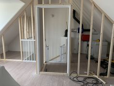 an unfinished room with white walls and wood framing on the wall, in front of a stair case