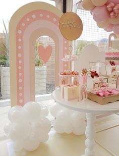 a pink and white dessert table with balloons