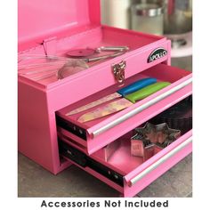 a pink toy kitchen with utensils and other items in the drawer that is open