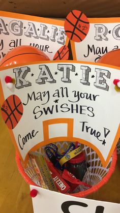 a basket filled with candy and basketballs sitting on top of a table next to a sign