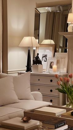 a living room filled with white furniture and lots of flowers on top of a coffee table