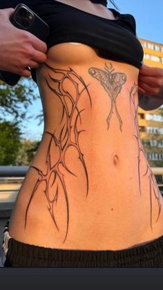 a woman with a butterfly tattoo on her stomach is holding onto the side of her body