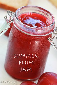 a jar filled with plum jam sitting on top of a table