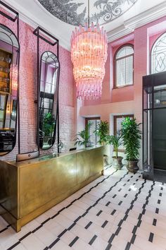 a pink and gold lobby with chandelier hanging from the ceiling