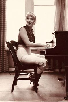 a black and white photo of a woman sitting at a piano