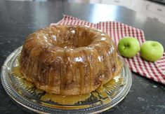 a bundt cake sitting on top of a glass plate next to two green apples