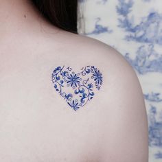 a blue heart tattoo on the back of a woman's left shoulder and chest