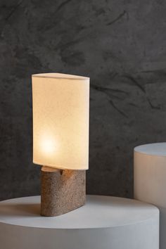 a lamp sitting on top of a white table next to a gray stone wall and floor