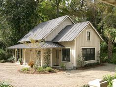 a white house with a metal roof surrounded by trees