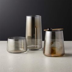 three glass vases sitting next to each other on top of a white countertop