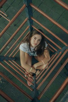 a young woman is sitting on the ground with her hands folded over her knees and looking down